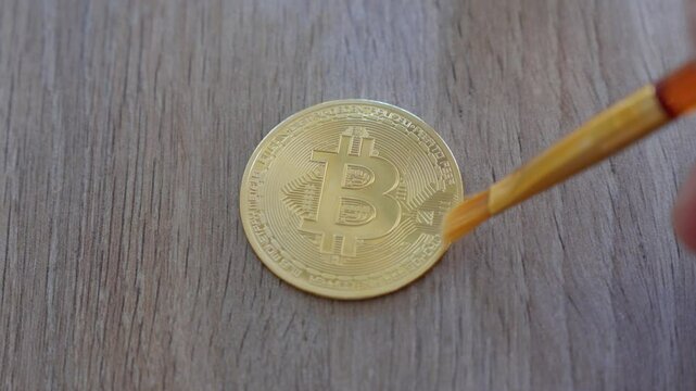close-up shot of a person cleaning their golden bitcoin on a table