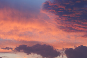Fototapeta premium Cloudy sky and orange and pink sun lights reflecting from clouds