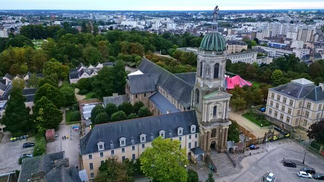 Notre-Dame-en-Saint-Melaine French abbey church, Thabor park in background. Rennes, Ille-et-Vilaine in Brittany, France. Aerial drone backward
