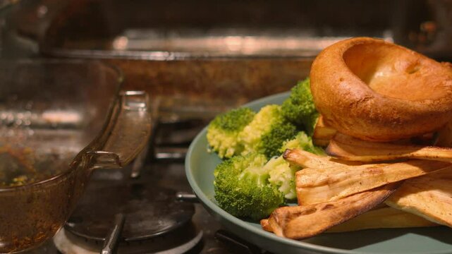 Pan From Empty Cooking Glass Trays to Reveal Traditional British Roast Dinner Plate with Vegetables including Parsnips, Broccoli, Roast Potatoes, Carrots and Yorkshire Pudding on Top 4K