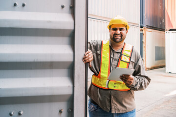 A smiling worker in safety gear stands by a shipping container, holding a clipboard, showcasing a positive attitude and commitment to safety in logistics. International shipping business management.