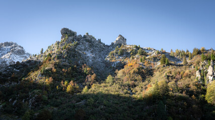 Beautiful autumn day in the french alps with colored trees and snowy moutains. Sunny day, blue sky