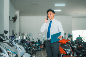 male sales manager making a call using a cell phone while standing in a motorcycle showroom