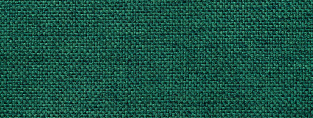 Texture dark green background from woven textile material with wicker pattern, macro. Structure vintage emerald fabric