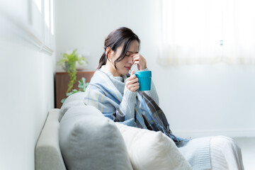 リビングのソファに座る体調不良の女性