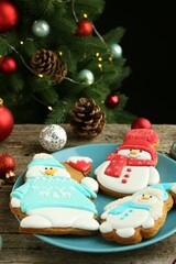 Delicious cookies in shape of snowmen and Christmas decor on wooden table