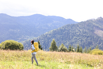 Fototapeta premium Young woman with backpack hiking in mountains
