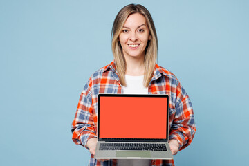 Young IT woman she wears red shirt t-shirt casual clothes hold use work on laptop pc computer with blank screen workspace area isolated on plain pastel light blue cyan background. Lifestyle concept.