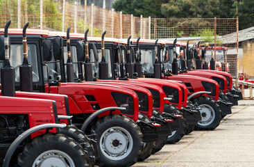Agricultural equipment dealership background. Line of different red colored farm tractors.