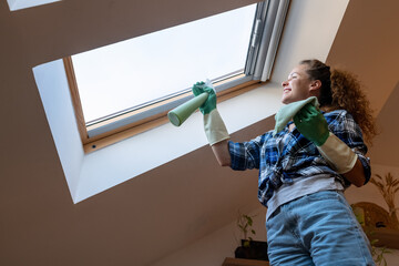 A woman washing and cleaning a skylight window at home.