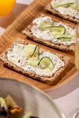 A fresh salad with feta, walnuts, apples, and crackers with cucumber and tsasiki, accompanied by orange juice