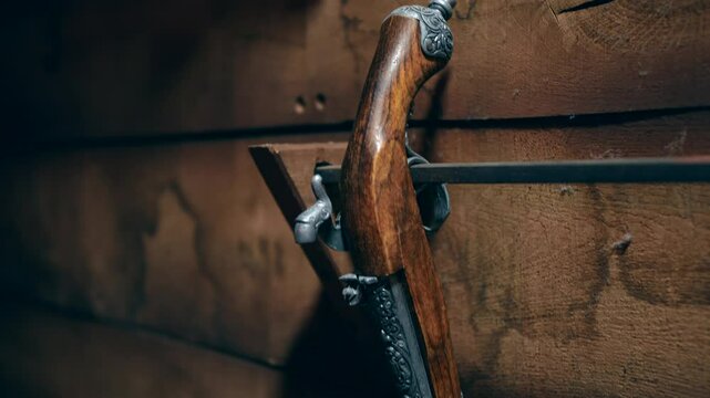An antique flintlock pirate pistol mounted on a wooden ship wall, highlighting its intricate metal detailing and polished wooden grip