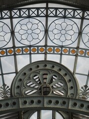 Close-up of a decorative metal and glass ceiling structure in Brussels, featuring intricate floral patterns and geometric designs in an ornate architectural style
