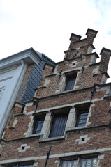 Detail of a traditional brick building with stepped gable architecture and stone-framed windows, showcasing historical European design elements
