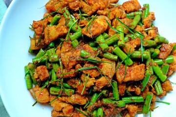Stir fried crispy pork belly and yard long bean with ginger red curry paste, Authentic Thai food.
