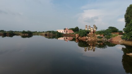 Obraz premium Scenic Reflections of a Riverside well and Rural Landscape Under Clear Skies