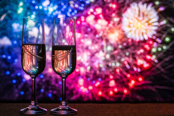 Two Flutes Of Champagne Against A Fireworks Show, Symbolizing Celebration And Elegance For Special Occasions Such As New Year's Eve, Weddings, And Celebrations. Year-End Background With Copy Space.