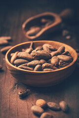 Organic cocoa beans in wooden bowl on wooden background