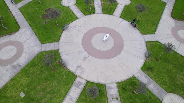 Drone circling around a young girl performing Peruvian native dance Marinera at urban park