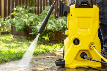 Fototapeta premium Washer Karcher. High Pressure Washing Paving Stones Blocks in Garden on Green Background. Cleaning Service.