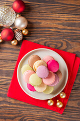 Macarons in a plate with Christmas balls on a red napkin. Christmas background. Vertical orientation, top view.