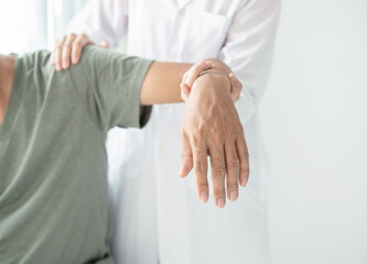 Female physiotherapists provide physical assistance to male patients with shoulder injuries massaging their shoulders for muscle recovery in the rehabilitation center. Physiotherapy concepts