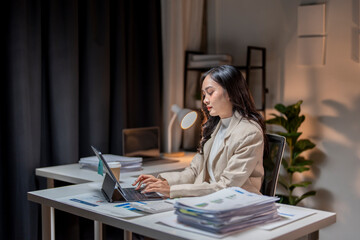 Focused asian businesswoman working late on tablet at desk in office