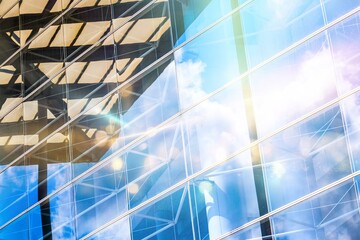 A close-up of a modern building in Hong Kong, with a glass facade reflecting the sky and clouds.