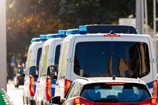 Scene back view many german police van cars drive in city urban road traffic light center downtown on sunny day. Civil emergency law security traffic service vehicle Europe. Event safety service