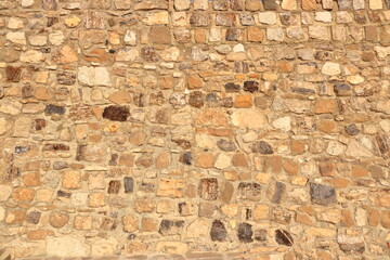 yellow beige natural stone wall of different sized stones, traditional crafts