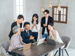 オフィスで拍手する幅広い世代のビジネスパーソンのチーム