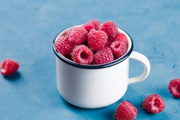 Mug with raspberry and blue. food fresh sweet concept. mug with raspberries on a blue . a mug with...