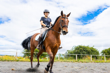 woman riding a brown horse in outdoor arena