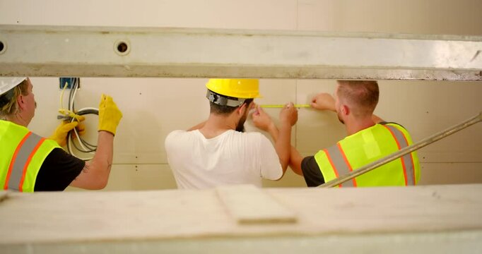 A dedicated team of construction workers in bright safety vests and hard hats is actively engaged in a remodeling project, showcasing their teamwork, dedication, and professionalism in the industry