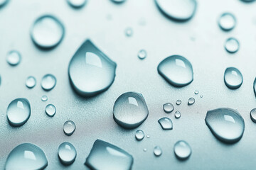 Close-up of water droplets on a smooth surface, showcasing detailed reflections and varying sizes of droplets.