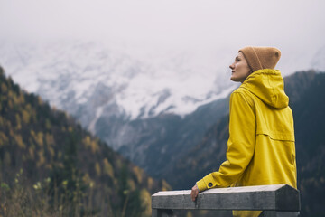 Woman in yellow jacket on nature background of mountains.