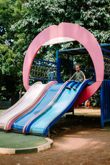 A child playing joyfully in a city playground, exploring swings and slides.