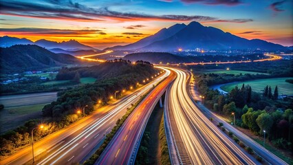 Fototapeta premium A stunning aerial view of light trails on a twilight highway with a majestic mountain backdrop
