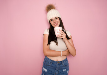 Portrait of a Young beautiful girl over pink wall holding a hot cup of coffee