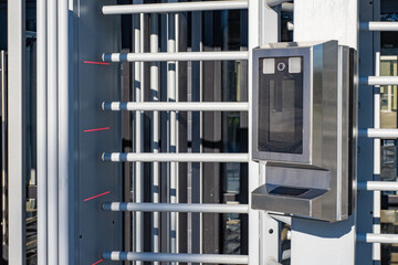 Full height fragment of turnstiles. Barcode scanner at entrance gates to stadium. Rotor turnstile is illuminated by sunlight. Pedestrian gateway for access control. Full height turnstile in metro