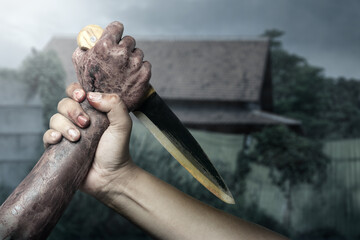 Zombie hand with bloody wound fighting with man on midnight background. Zombie hand holding knife...