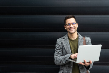 Portrait of young businessman standing outside office building. Successful professional office...