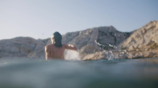 Woman jumping and playing in the water of a calanque on the Frioul islands at sunset, Marseille, France