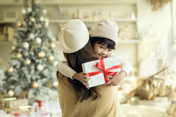 Merry Christmas. Happy mother embracing her daughter while received a gift on christmas festival