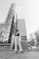 Stylish Woman Posing in Striped Trousers Against Modern Urban Architecture