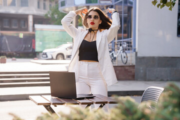 Confident Businesswoman in Stylish Striped Suit Adjusting Hair Outdoors