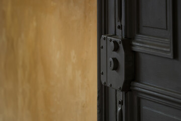 An Elegant Black Door with an Industrial Lock Set Against a Beautifully Textured Wall