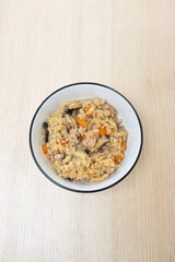A bowl of steam rice with chicken and mushroom.