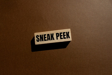 Sneak peek message written on wooden block with brown background. Conceptual sneak peek symbol. Copy space.