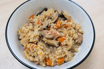 A bowl of steam rice with chicken and mushroom.